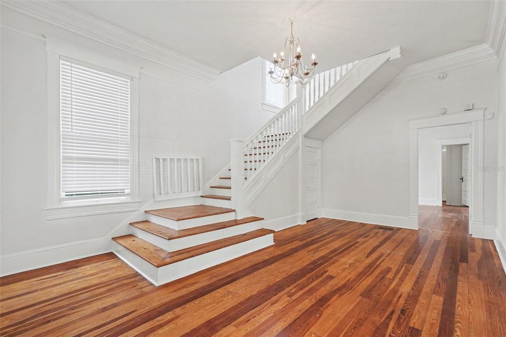 A bright room features hardwood floors, a white staircase, and a crystal chandelier — 501 W EUCLID AVENUE, TAMPA, FL
