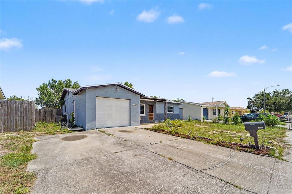 A single-story house with a blue exterior, a front-facing garage, and a concrete driveway — 8143 HIXTON DRIVE, PORT RICHEY, FL