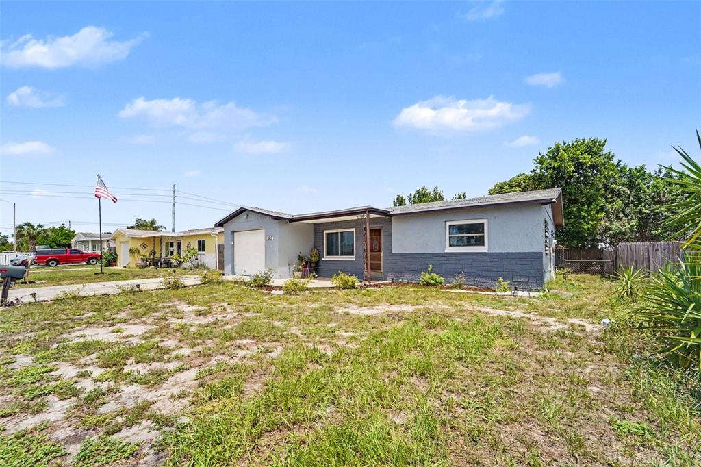 A single-story house with a gray exterior, a front-facing garage, and a large grassy yard — 8143 HIXTON DRIVE, PORT RICHEY, FL