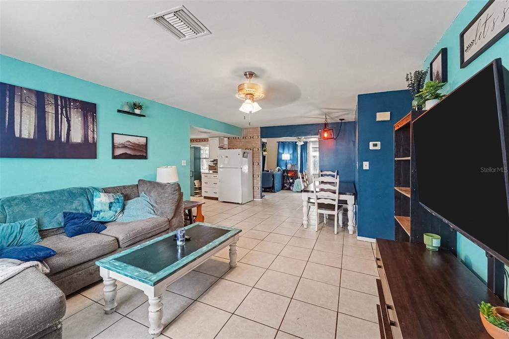 A living room with turquoise and dark blue walls, tile flooring, and a dining area — 8143 HIXTON DRIVE, PORT RICHEY, FL