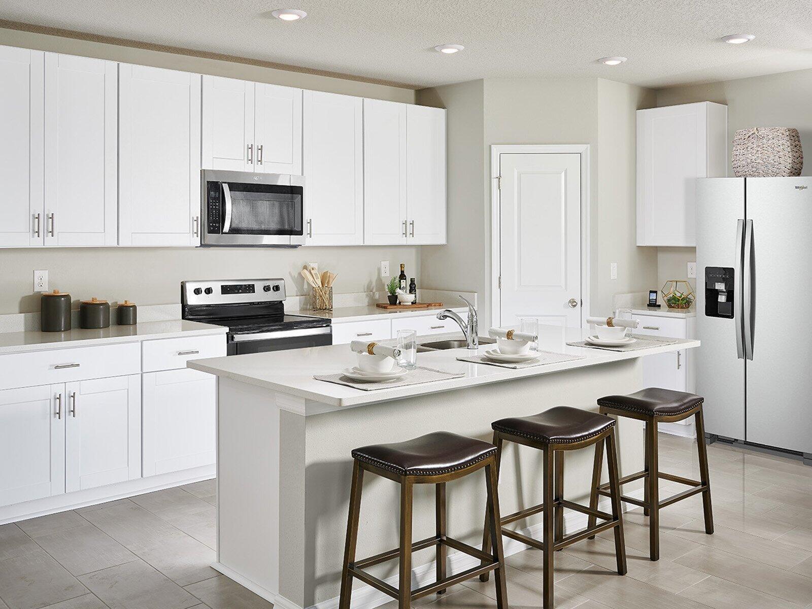 A kitchen features white cabinets, stainless steel appliances, a center island, and three bar stools — 5457 Hampton Park Circle, Vero Beach FL 32966, VERO BEACH, FL
