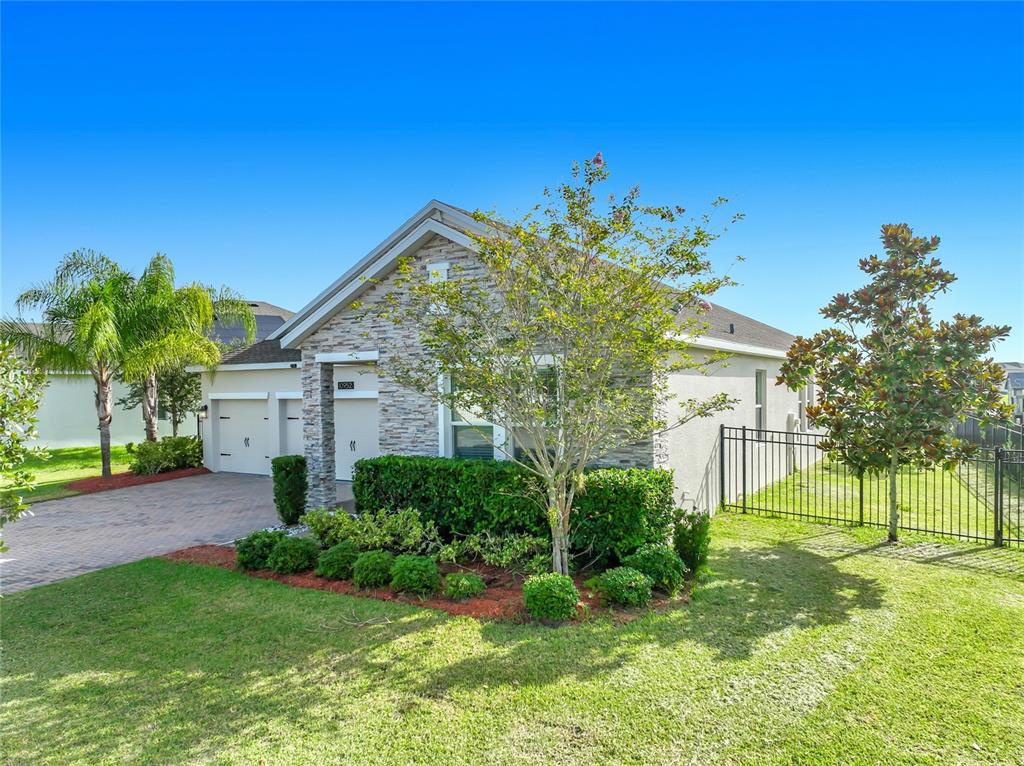 A single-story house with a stone facade, a paved driveway, and a fenced side yard — 10952 LONGLEAF WOODS DRIVE, ORLANDO, FL