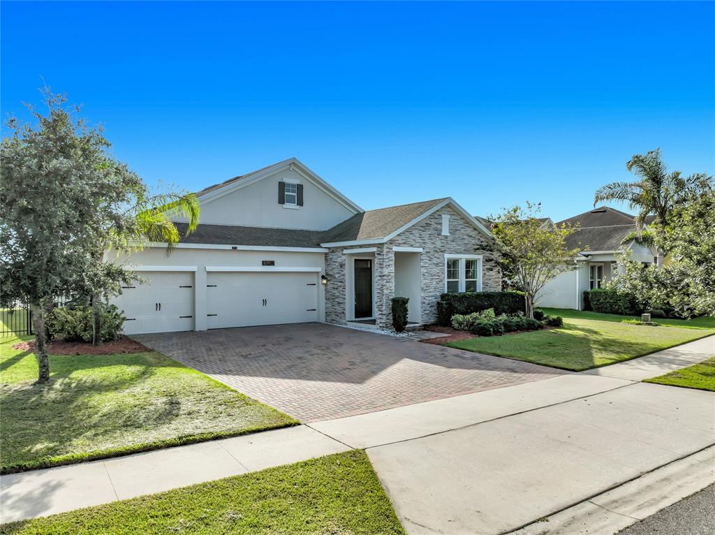 A single-story house with a stone facade, two-car garage, and a brick paver driveway — 10952 LONGLEAF WOODS DRIVE, ORLANDO, FL