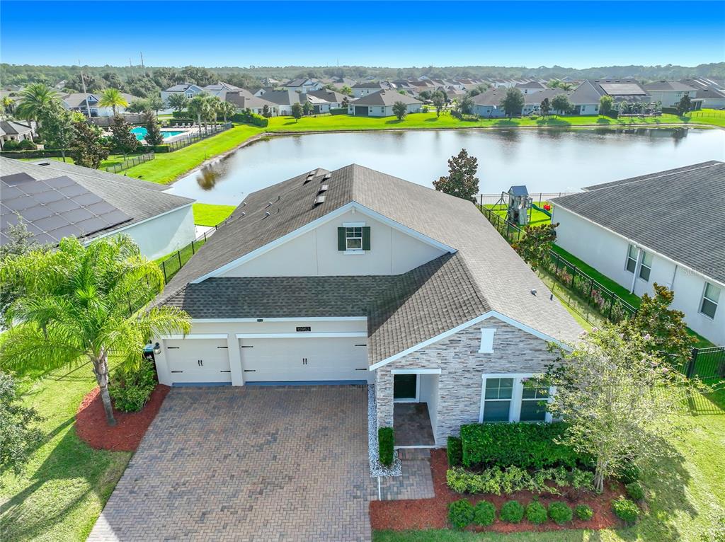 An aerial view of a single-story house with a stone facade, garage, and backyard pond — 10952 LONGLEAF WOODS DRIVE, ORLANDO, FL