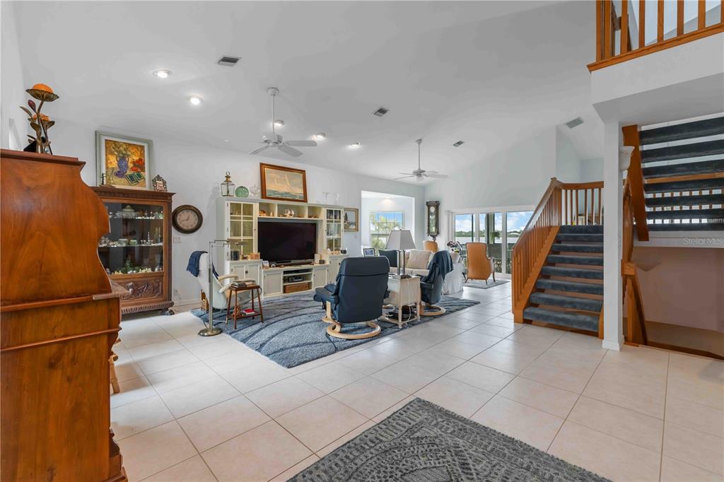 A spacious living room features tile flooring, a staircase, and a view of the water — 7795 MANASOTA KEY ROAD, ENGLEWOOD, FL
