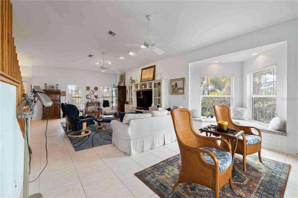 A spacious living room features tile floors, a white sofa, wicker chairs, and a bay window — 7795 MANASOTA KEY ROAD, ENGLEWOOD, FL