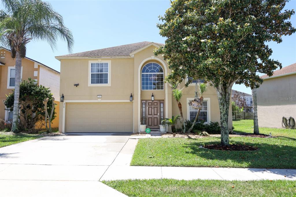 A two-story tan house with a two-car garage and a large arched window — 210 PINEFIELD DRIVE, SANFORD, FL