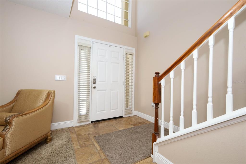 An entryway features a white front door, tiled floor, and a staircase with white railings — 210 PINEFIELD DRIVE, SANFORD, FL