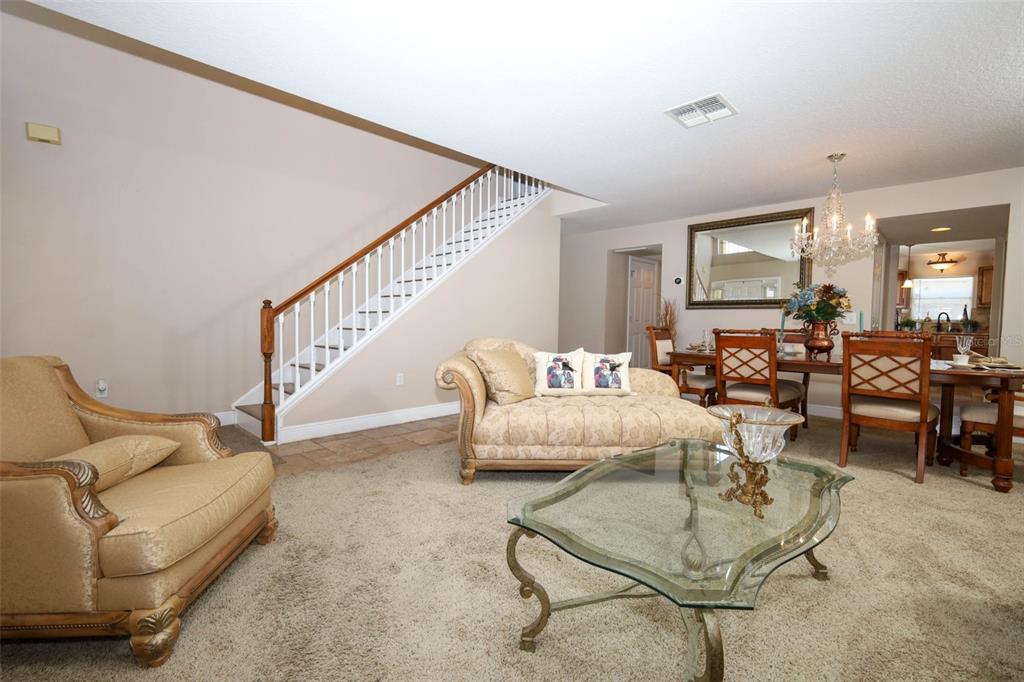 A living and dining area with carpeted floors, a staircase, and a glass coffee table — 210 PINEFIELD DRIVE, SANFORD, FL