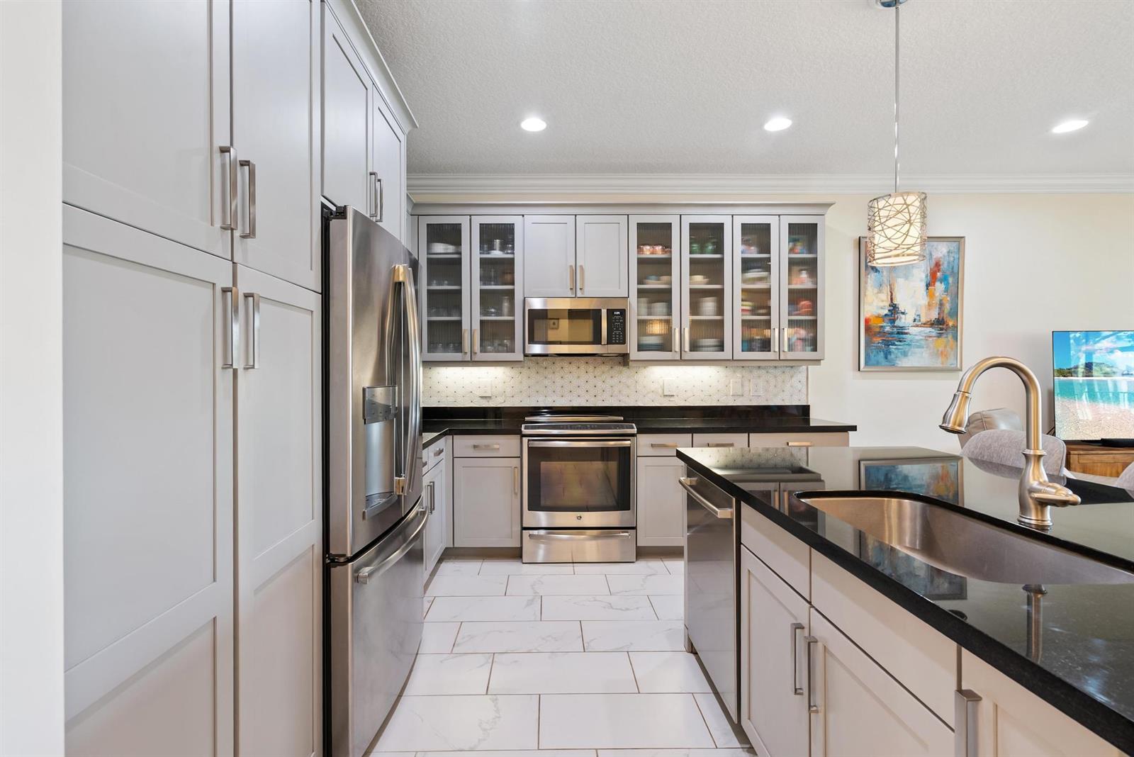 A modern kitchen features light gray cabinetry, stainless steel appliances, and black granite countertops — 13809 Imperial Topaz Trail, Delray Beach FL 33446, DELRAY BEACH, FL