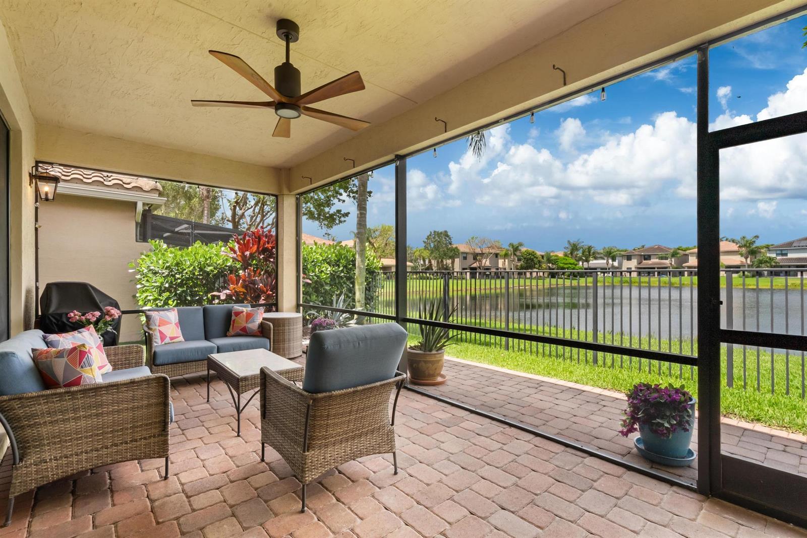 A screened-in patio features wicker furniture, a ceiling fan, and a view of a lake — 13809 Imperial Topaz Trail, Delray Beach FL 33446, DELRAY BEACH, FL