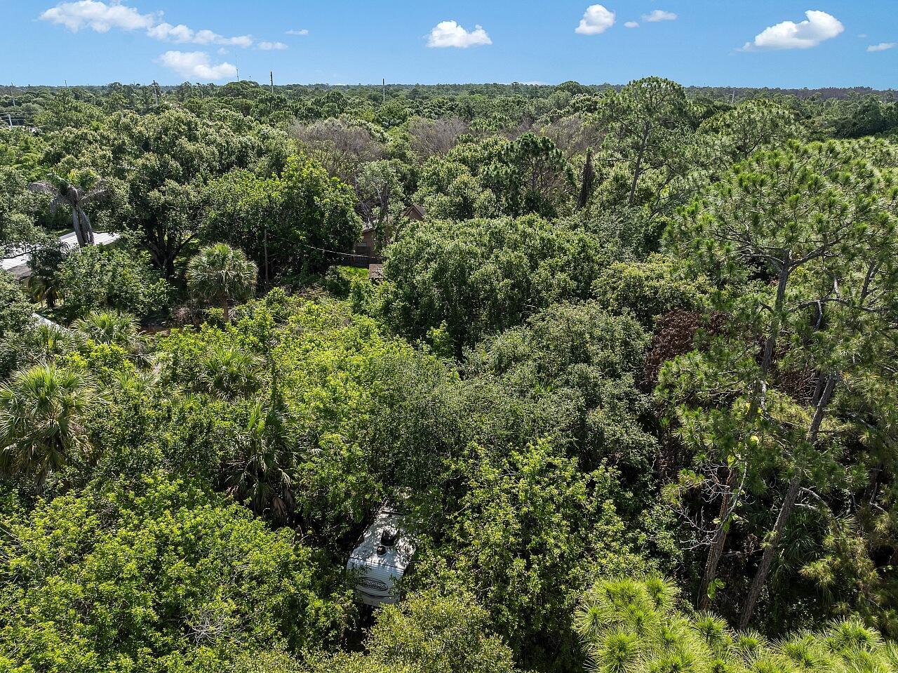 An aerial view shows a white recreational vehicle parked amidst dense trees and foliage — 564 30th Avenue SW, Vero Beach FL 32968, VERO BEACH, FL