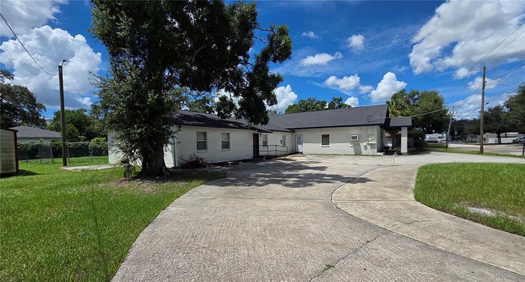 A white, single-story building with a dark roof sits behind a large concrete driveway — 3103 E LAKE AVENUE, TAMPA, FL