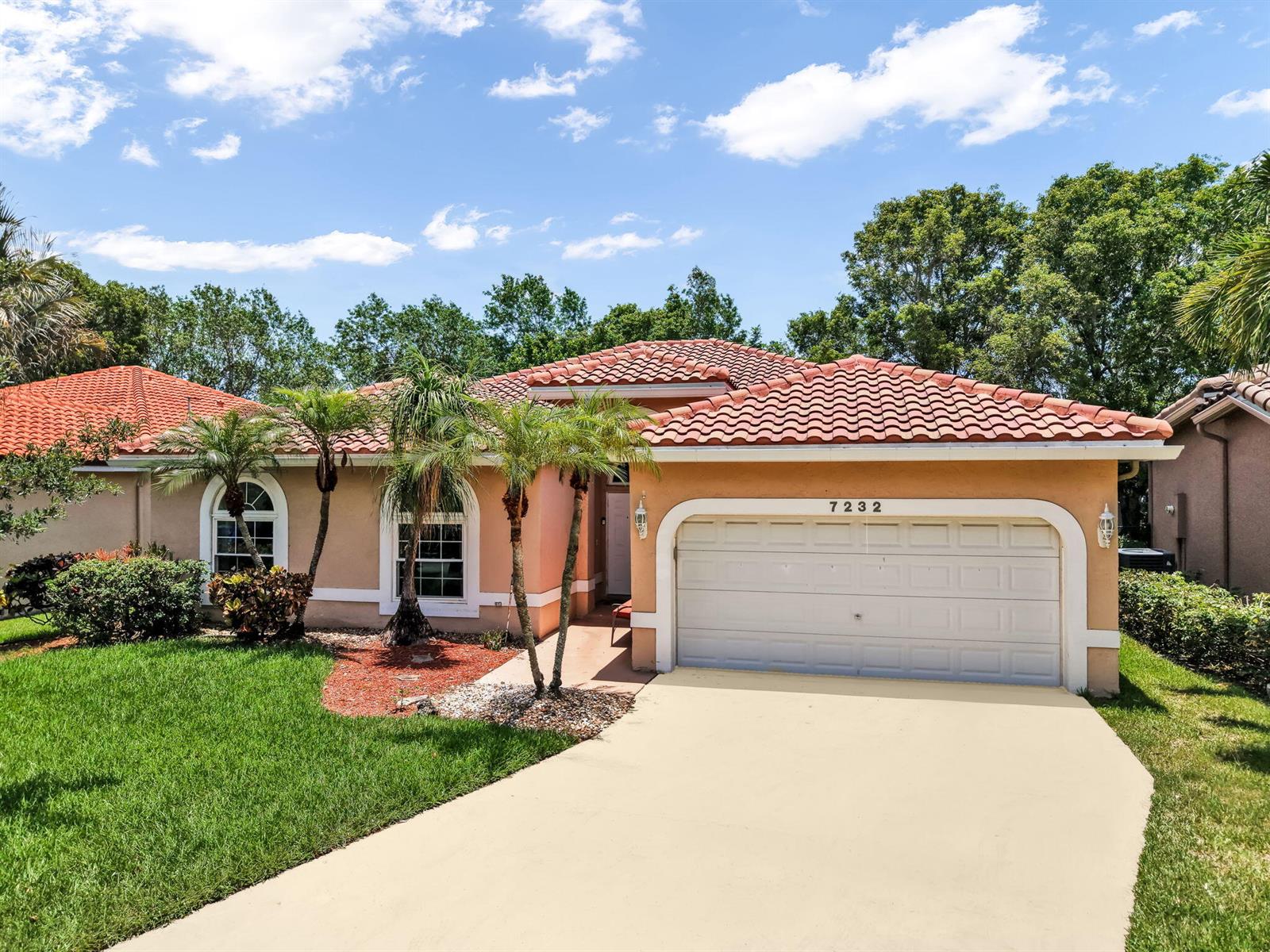 A single-story house with a terracotta tile roof, beige stucco walls, and a two-car garage — 7232 NW 58th Way, Parkland FL 33067, PARKLAND, FL