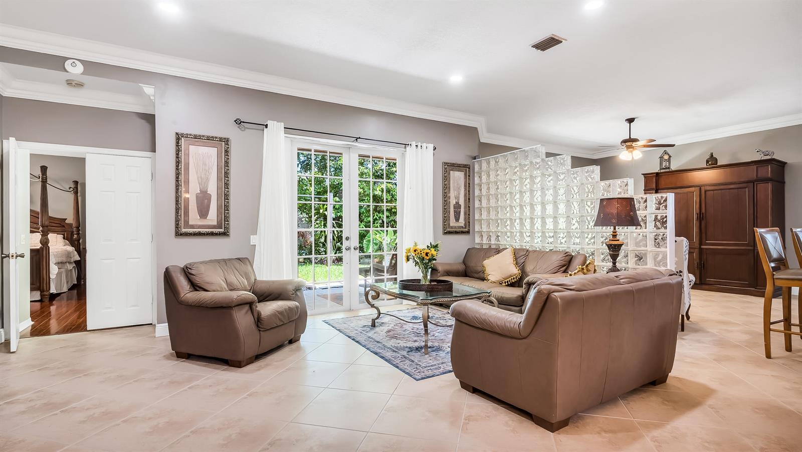 A living room features leather furniture, a glass coffee table, and a glass block wall — 7232 NW 58th Way, Parkland FL 33067, PARKLAND, FL