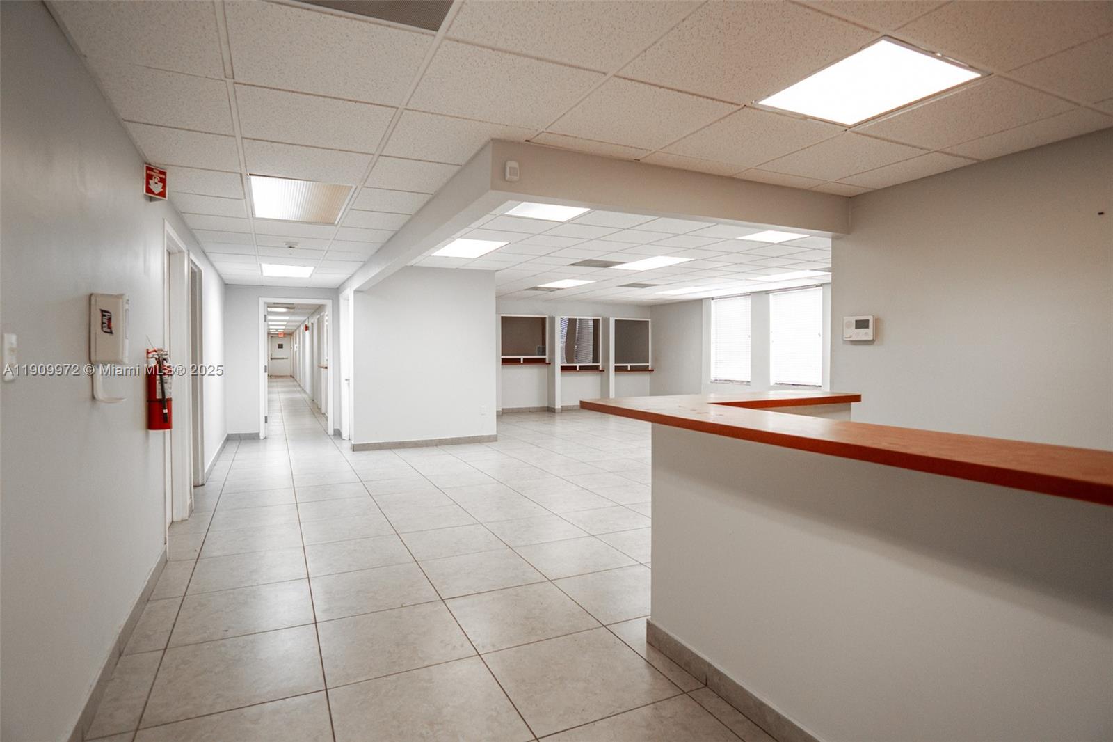 An office interior features a reception desk, tiled flooring, a drop ceiling, and a hallway — 1901 SW 1st St, Miami FL 33135, MIAMI, FL