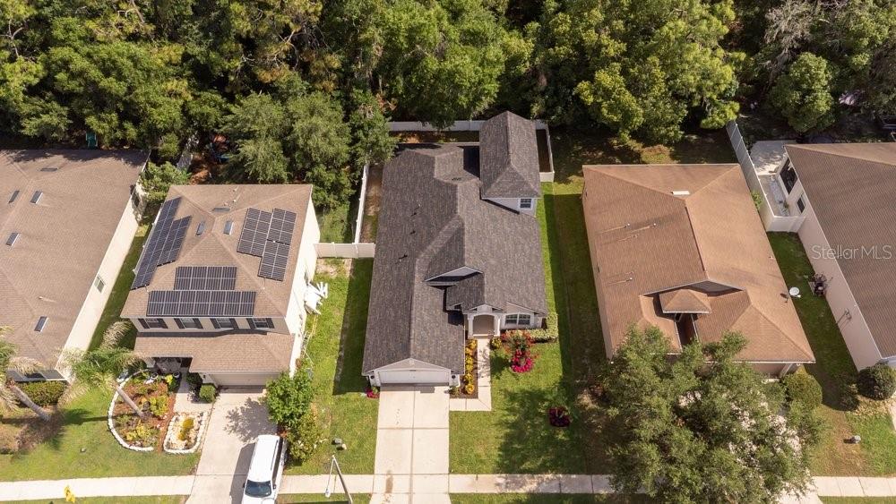 An aerial view shows three suburban houses with shingled roofs and green lawns — 6249 TWIN BRIDGES DRIVE, ZEPHYRHILLS, FL