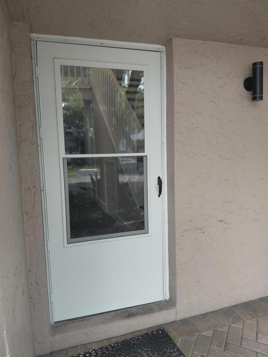 A white storm door with glass panels is installed in a stucco exterior entryway — 2147 Discovery Circle W, Deerfield Beach FL 33442, DEERFIELD BEACH, FL