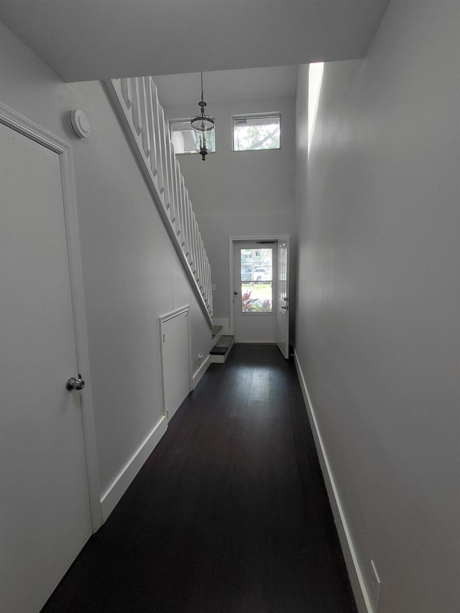 A narrow entryway features dark wood flooring, white walls, and a staircase leading upward — 2147 Discovery Circle W, Deerfield Beach FL 33442, DEERFIELD BEACH, FL