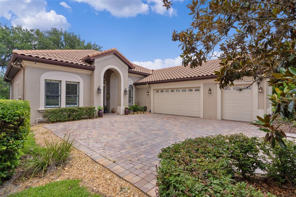 A single-story house with a beige stucco exterior, tile roof, and a paved driveway — 9429 SAN MIGUEL, HOWEY IN THE HILLS, FL