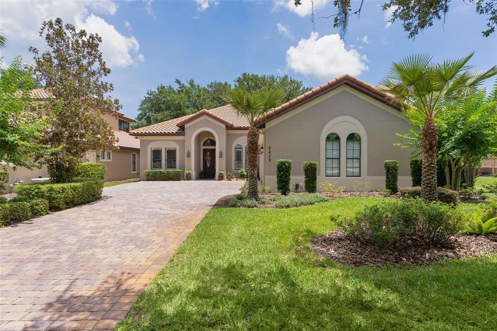 A single-story house with a paved driveway, arched entryway, and a tiled roof — 9429 SAN MIGUEL, HOWEY IN THE HILLS, FL