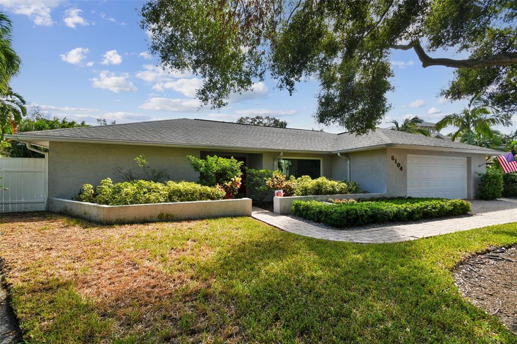 A single-story house with a beige stucco exterior, a two-car garage, and landscaped front planters — 5104 W SAN JOSE STREET, TAMPA, FL