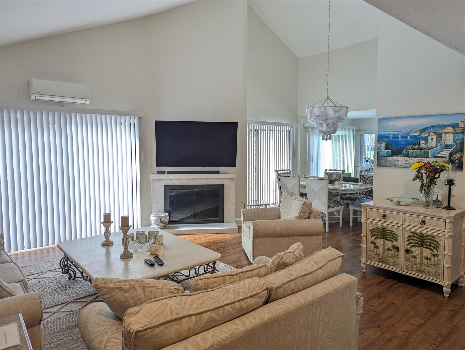 A living room with a fireplace, television, beige furniture, and an adjacent dining area — 17042 Traverse Circle, Jupiter FL 33477, JUPITER, FL