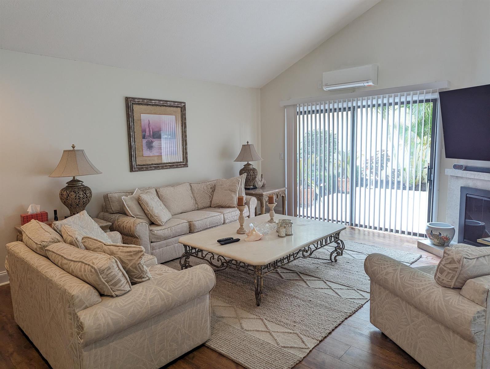A living room features beige patterned sofas, a stone coffee table, and a sliding glass door — 17042 Traverse Circle, Jupiter FL 33477, JUPITER, FL