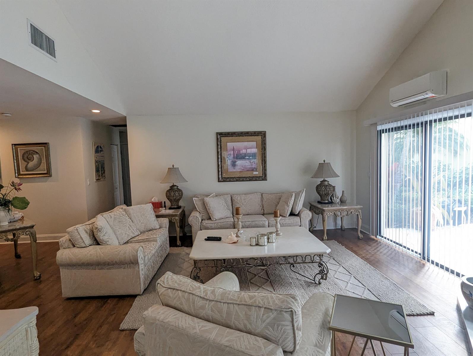 A living room features light-colored sofas, a central coffee table, and a sliding glass door — 17042 Traverse Circle, Jupiter FL 33477, JUPITER, FL