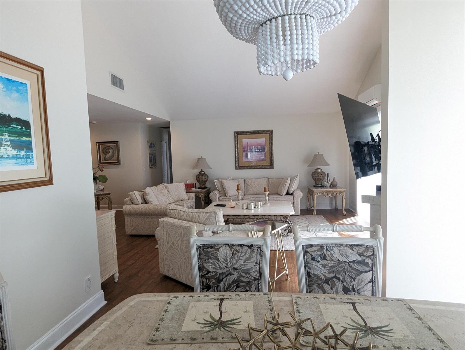 A living room with a beaded chandelier, neutral furniture, and a television mounted on the wall — 17042 Traverse Circle, Jupiter FL 33477, JUPITER, FL