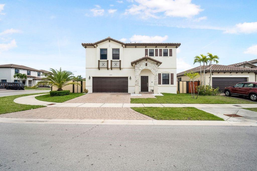 A two-story suburban house features a stucco exterior, a stone-accented entryway, and a garage — 12861 SW 229 th terrace, Miami FL 33170, MIAMI, FL