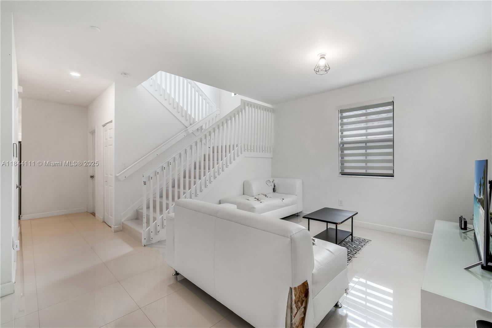 A living room features white tile floors, a white sofa, and a staircase with white railings — 12861 SW 229 th terrace, Miami FL 33170, MIAMI, FL