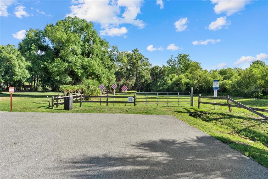 A paved driveway leads to a fenced grassy lot with a metal gate and trees — Lot 8 & 9 NUTMEG AVENUE, SARASOTA, FL