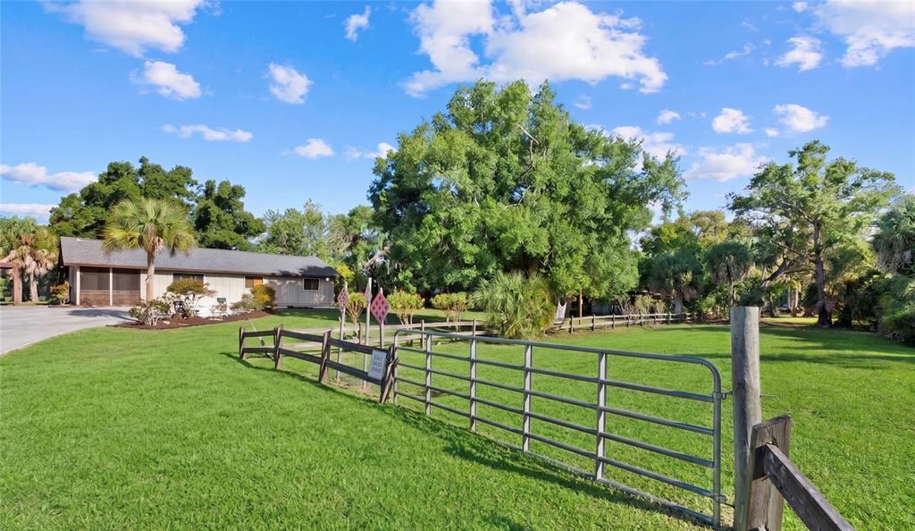 A metal gate and wooden fence enclose a grassy yard in front of a house — Lot 8 & 9 NUTMEG AVENUE, SARASOTA, FL