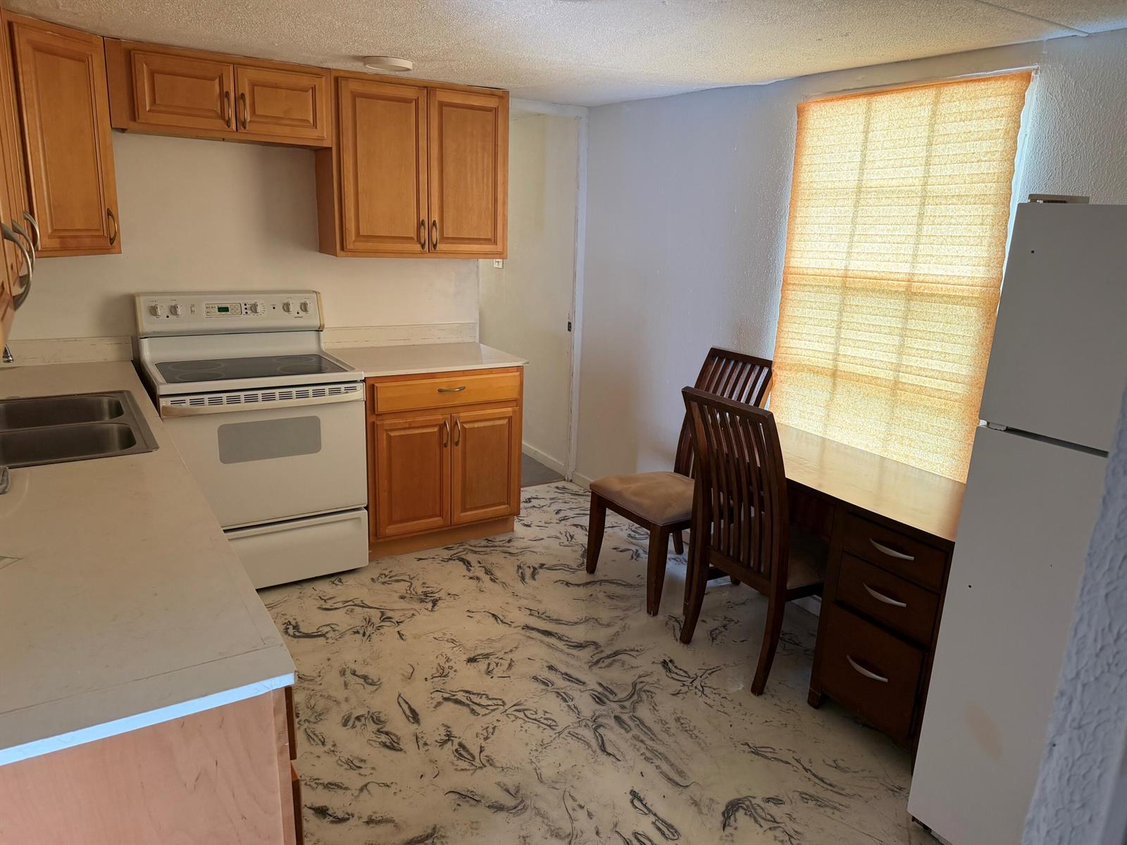 A kitchen with light wood cabinets, white appliances, and a patterned floor near a window — 8556 BERKLEY Drive, Davie FL 33324, DAVIE, FL