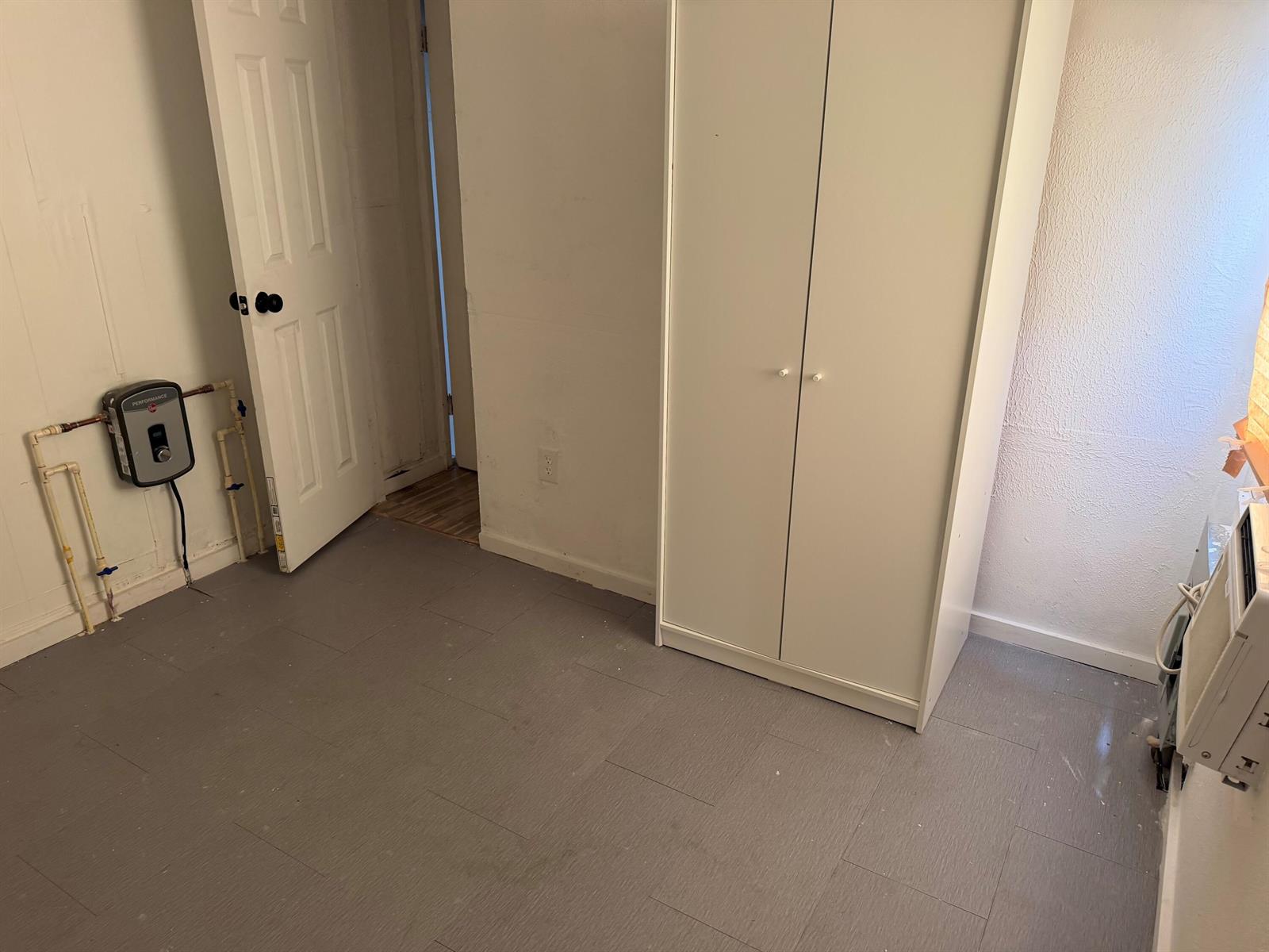 A room with gray flooring, a white wardrobe, and an electric water heater on the wall — 8556 BERKLEY Drive, Davie FL 33324, DAVIE, FL
