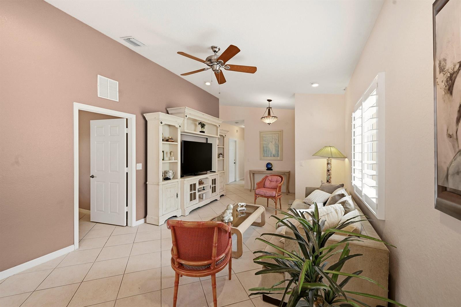 A living room features tile flooring, a white entertainment center, a sofa, and a ceiling fan — 2340 Windjammer Way, West Palm Beach FL 33411, WEST PALM BEACH, FL