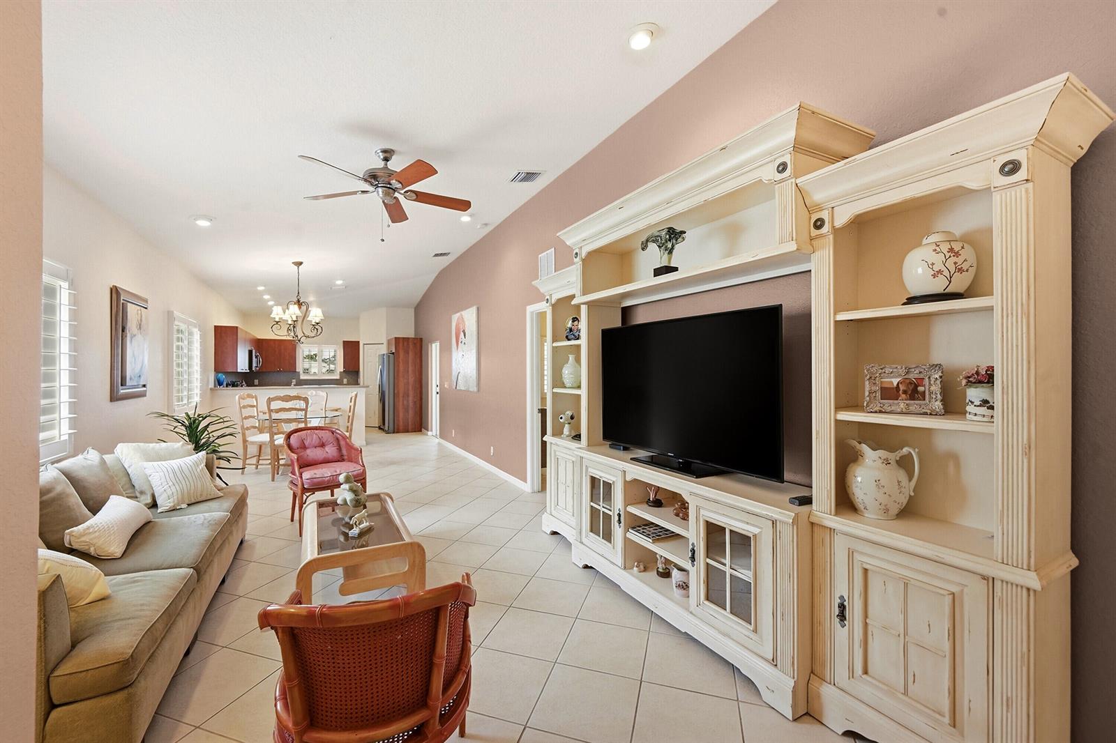 A living room with tile floors, a large entertainment center, and an open kitchen area — 2340 Windjammer Way, West Palm Beach FL 33411, WEST PALM BEACH, FL