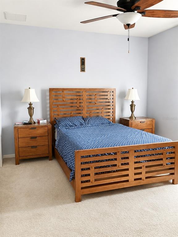 A bedroom features a wooden bed frame, two matching nightstands with lamps, and a ceiling fan — 10311 GREYSTONE RIDGE COURT, RIVERVIEW, FL