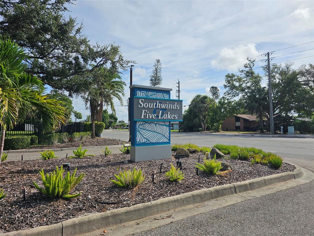 A sign for Southwinds Five Lakes stands in a landscaped garden bed beside a road — 3441 51ST AVENUE CIRCLE W UNIT 213, BRADENTON, FL
