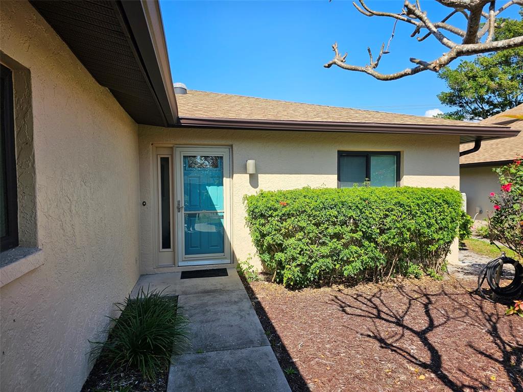 A concrete walkway leads to the front entrance of a house with beige stucco walls — 3441 51ST AVENUE CIRCLE W UNIT 213, BRADENTON, FL