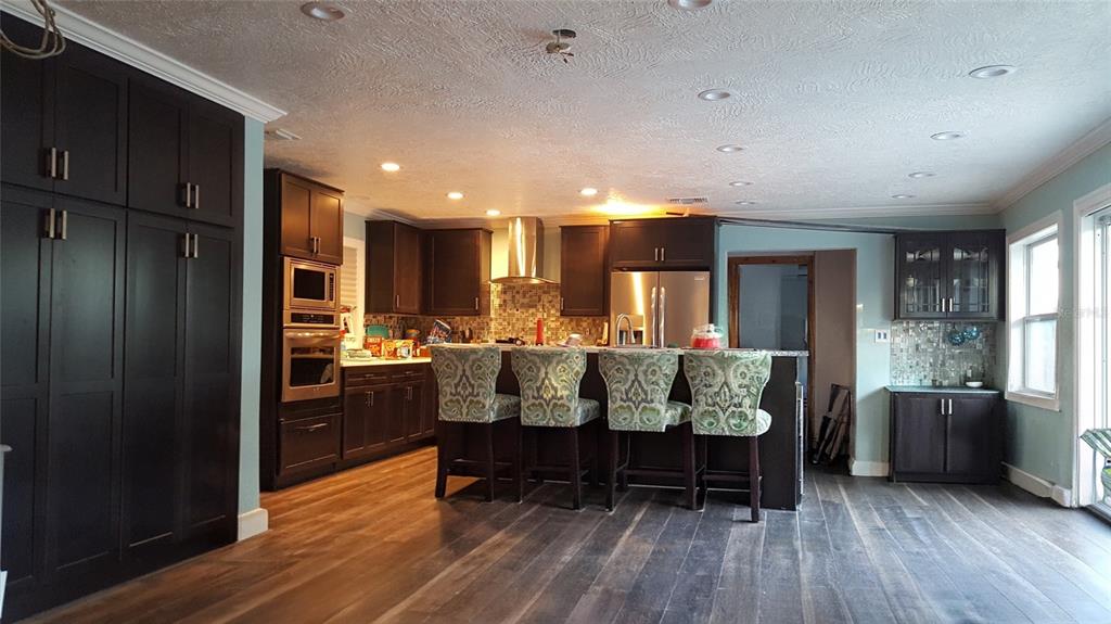A kitchen features dark cabinetry, stainless steel appliances, a breakfast bar, and wood-look flooring — 2054 EASTBROOK BOULEVARD, WINTER PARK, FL
