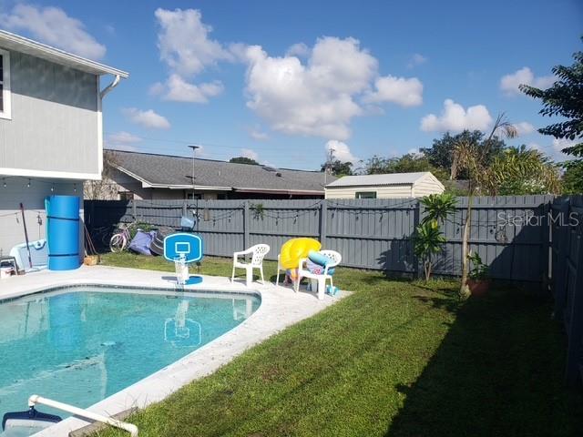 A backyard features a swimming pool, a basketball hoop, patio chairs, and a wooden fence — 2054 EASTBROOK BOULEVARD, WINTER PARK, FL