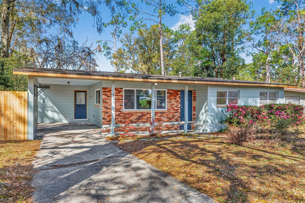 A single-story house with a brick facade, a carport, and a front yard with trees — 2200 NE 16TH TERRACE, GAINESVILLE, FL
