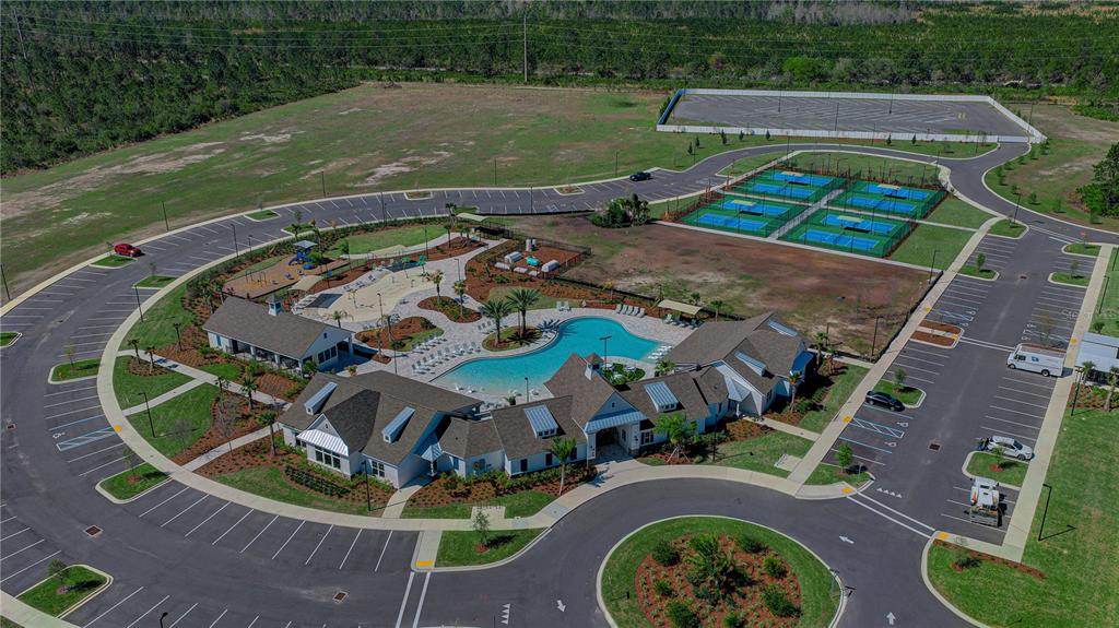 Aerial view of a community clubhouse featuring a swimming pool, playground, and tennis courts — 21 HULETT WOODS ROAD, PALM COAST, FL