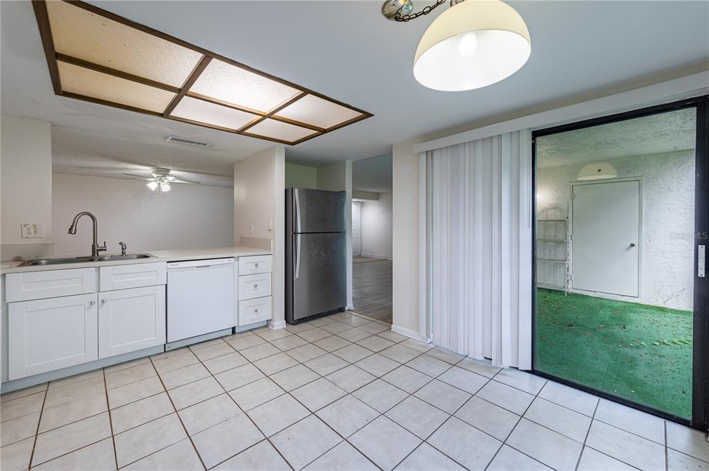 A kitchen with white cabinets, tile flooring, and a sliding glass door to a patio — 7873 NIAGARA AVENUE UNIT 1803, TAMPA, FL