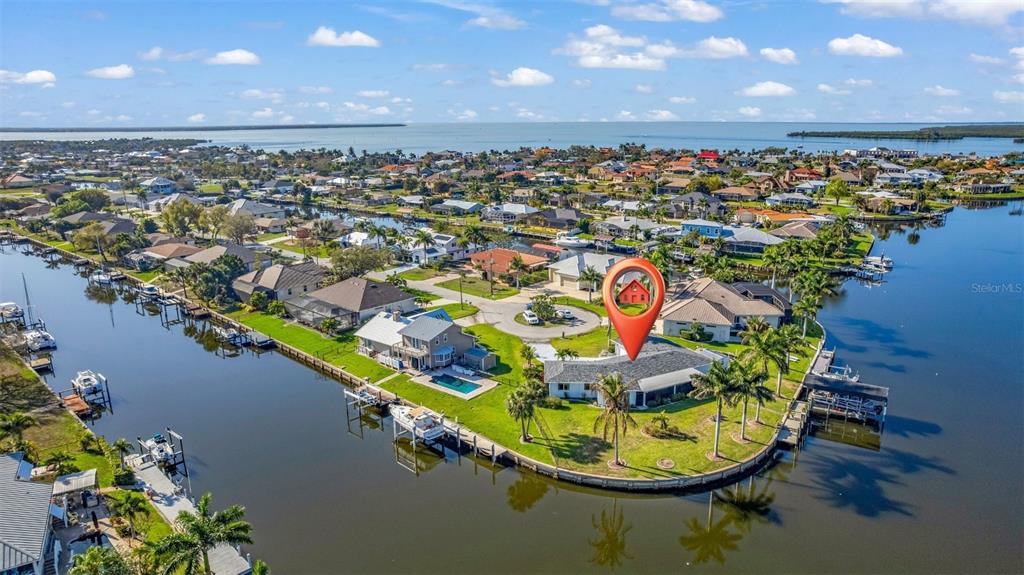 An aerial view shows a waterfront house with a pool on a canal-side lot — 138 COLONIAL STREET SW, PORT CHARLOTTE, FL
