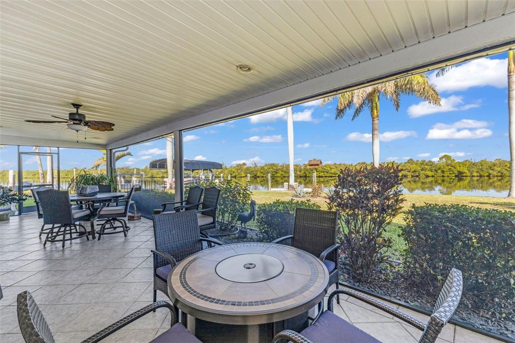 A screened-in patio features tile flooring, outdoor furniture, and a view of a canal — 138 COLONIAL STREET SW, PORT CHARLOTTE, FL