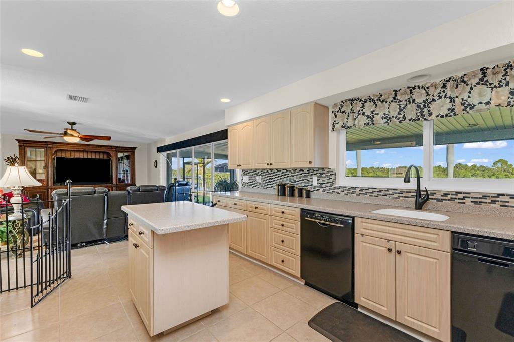 A kitchen with light wood cabinets, a center island, and a view of the outdoors — 138 COLONIAL STREET SW, PORT CHARLOTTE, FL