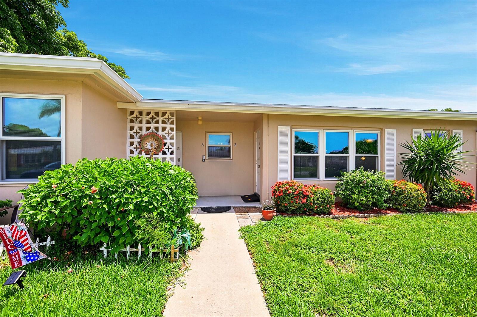 The exterior of a single-story house features a concrete walkway, decorative screen wall, and landscaping — 295 High Point Boulevard # B, Boynton Beach FL 33435, BOYNTON BEACH, FL